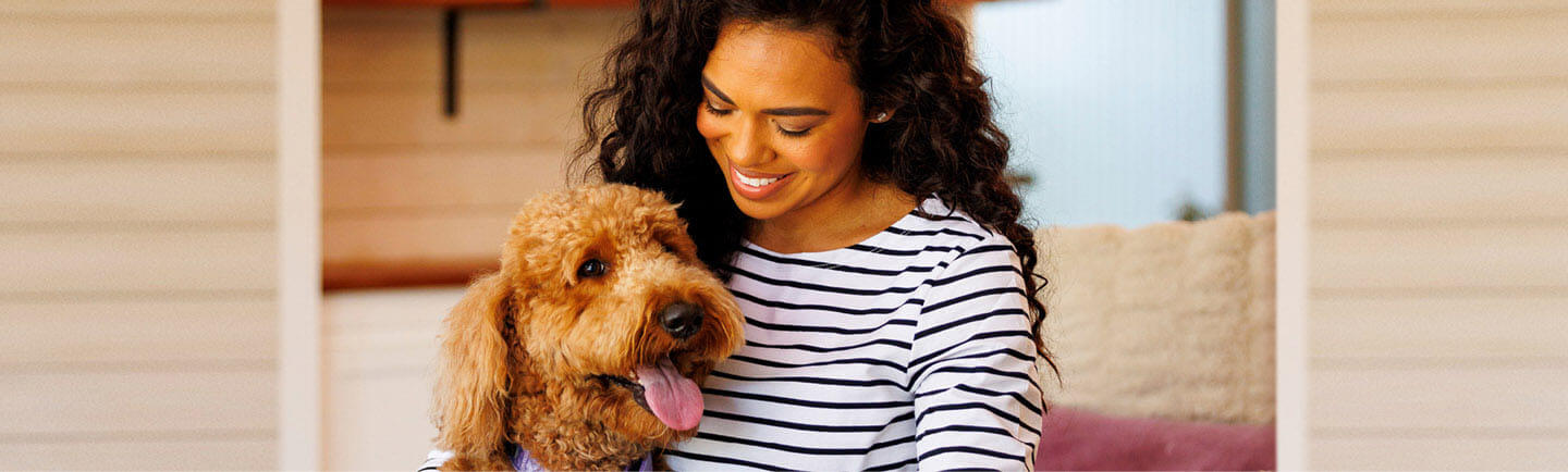 Happy-woman-smiling-at-her-Labradoodle-dog