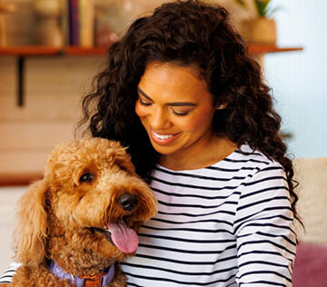 Happy-woman-smiling-at-her-Labradoodle-dog